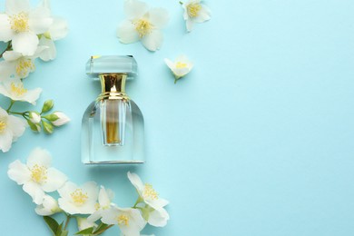 Photo of Bottle of perfume and beautiful jasmine flowers on light blue background, flat lay. Space for text