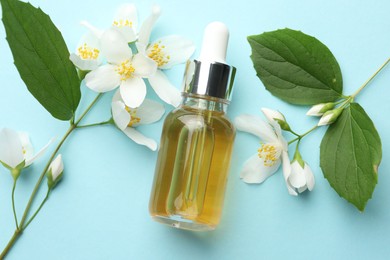 Photo of Essential oil, jasmine flowers and green leaves on light blue background, flat lay