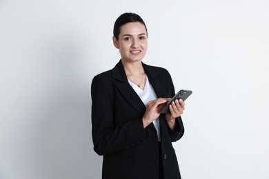 Photo of Confident business woman in suit with smartphone on light background