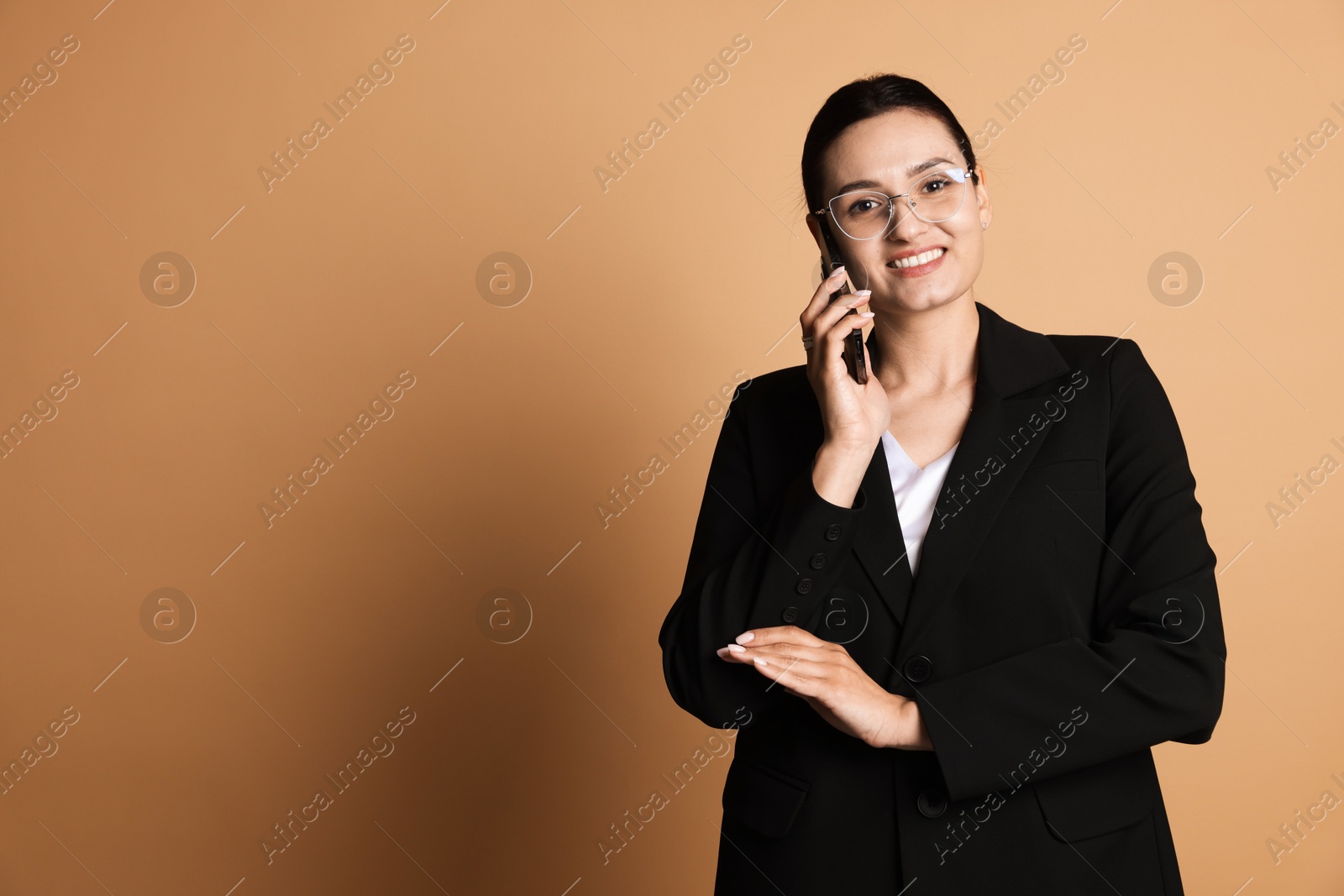 Confident business woman in suit talking on phone against beige background. Space for text Photo of Confident business woman in suit talking on phone against beige background. Space for text
