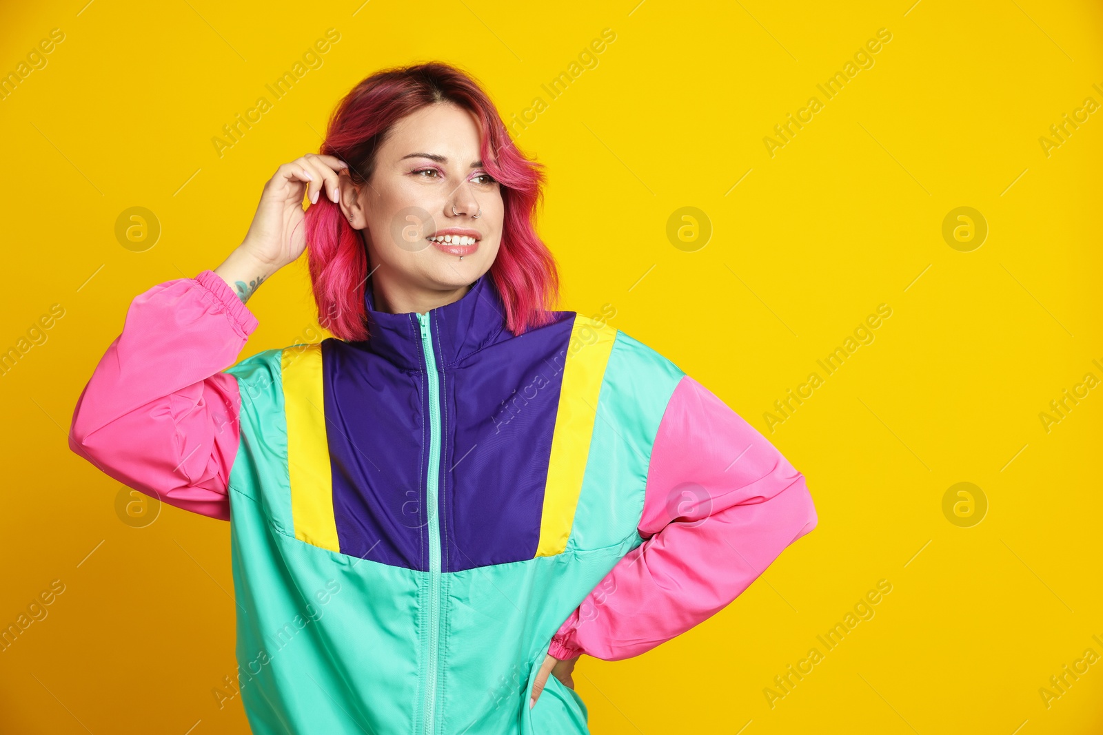Beautiful woman with pink dyed hair on yellow background, space for text Photo of Beautiful woman with pink dyed hair on yellow background, space for text