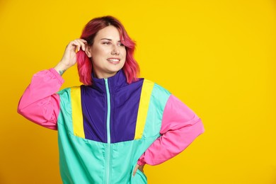 Photo of Beautiful woman with pink dyed hair on yellow background, space for text