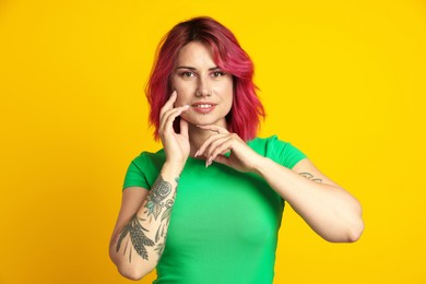 Photo of Beautiful woman with pink dyed hair on yellow background