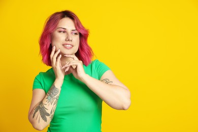 Photo of Beautiful woman with pink dyed hair on yellow background, space for text