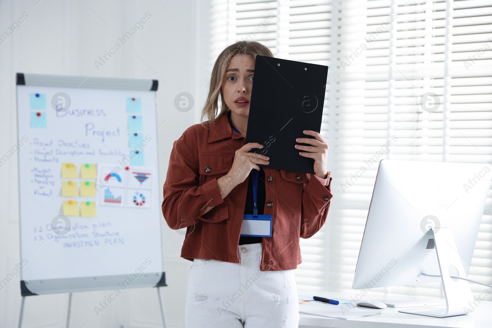 Fear of public speaking. Nervous woman with clipboard indoors Photo of Fear of public speaking. Nervous woman with clipboard indoors