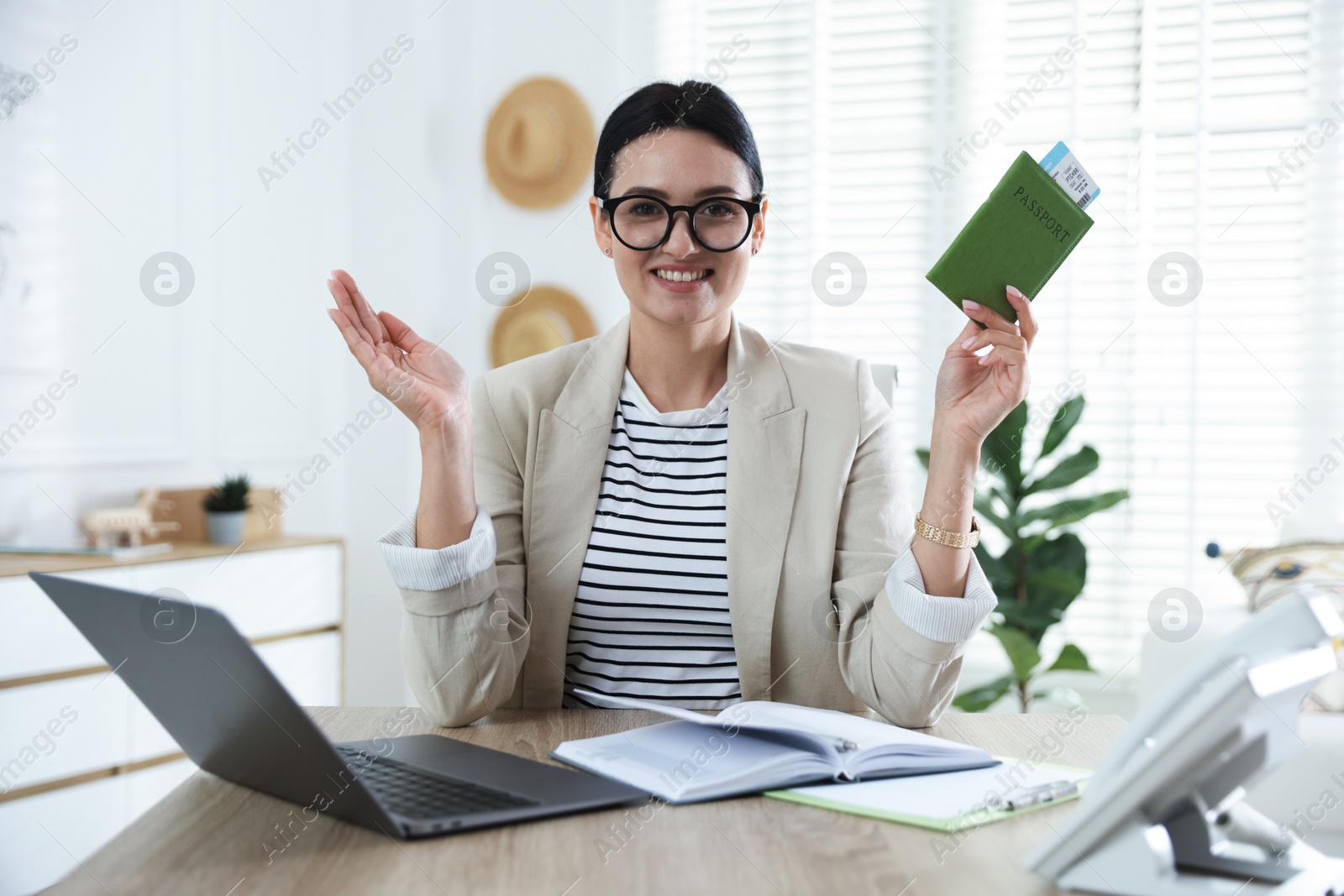Travel agent with passport and ticket at wooden table in office Photo of Travel agent with passport and ticket at wooden table in office