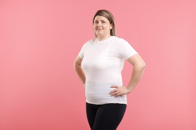 Photo of Weight loss. Plus size woman on pink background