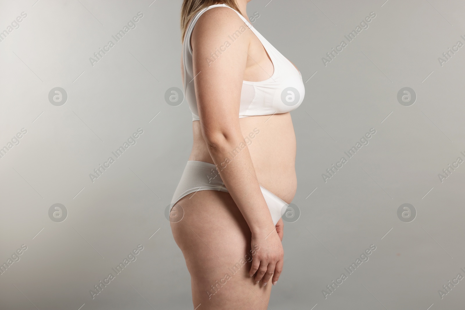 Weight loss. Plus size woman in underwear on gray background, closeup Photo of Weight loss. Plus size woman in underwear on gray background, closeup
