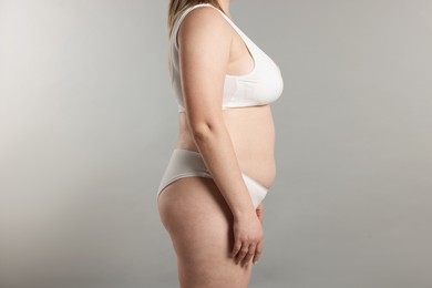 Photo of Weight loss. Plus size woman in underwear on gray background, closeup