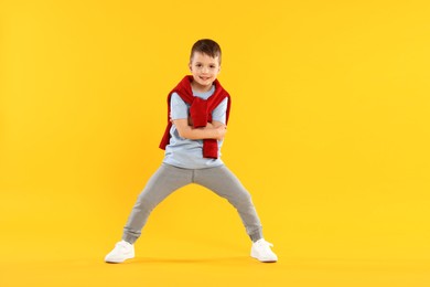 Photo of Happy little boy dancing on orange background
