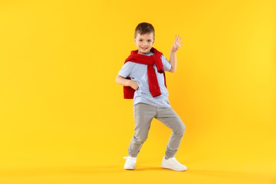 Photo of Happy little boy dancing on orange background