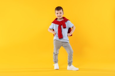 Photo of Happy little boy dancing on orange background