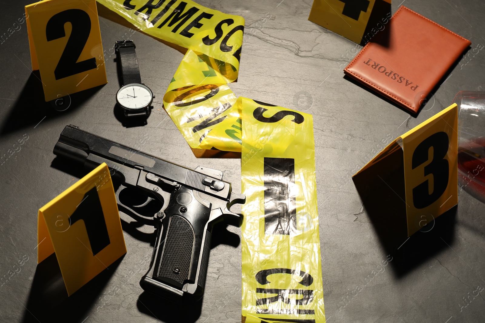 Forensic expertise. Crime scene with evidence, markers and police tape on grey background, closeup Photo of Forensic expertise. Crime scene with evidence, markers and police tape on grey background, closeup