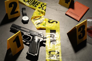Photo of Forensic expertise. Crime scene with evidence, markers and police tape on grey background, closeup
