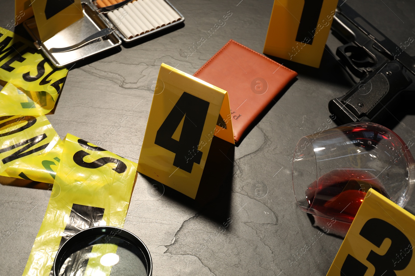 Forensic expertise. Crime scene with evidence, markers and police tape on grey background, closeup Photo of Forensic expertise. Crime scene with evidence, markers and police tape on grey background, closeup