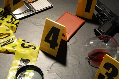 Photo of Forensic expertise. Crime scene with evidence, markers and police tape on grey background, closeup