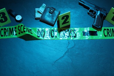 Photo of Forensic expertise. Crime scene with evidence, markers, police tape on blue background, flat lay and space for text. Color toned effect