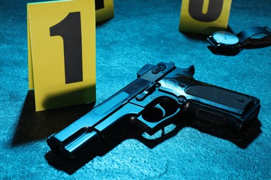 Photo of Forensic expertise. Crime scene with evidence, markers and police tape on blue background, closeup. Color toned effect