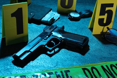 Photo of Forensic expertise. Crime scene with evidence, markers and police tape on blue background, closeup. Color toned effect