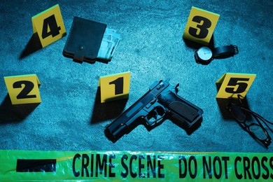 Photo of Forensic expertise. Crime scene with evidence, markers and police tape on blue background, flat lay. Color toned effect