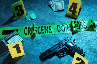 Photo of Forensic expertise. Crime scene with evidence, markers and police tape on blue background, closeup. Color toned effect