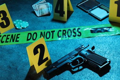 Photo of Forensic expertise. Crime scene with evidence, markers and police tape on blue background, closeup. Color toned effect