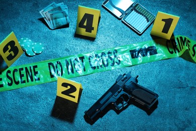 Photo of Forensic expertise. Crime scene with evidence, markers and police tape on blue background, flat lay. Color toned effect