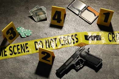 Photo of Forensic expertise. Crime scene with evidence, markers and police tape on grey background