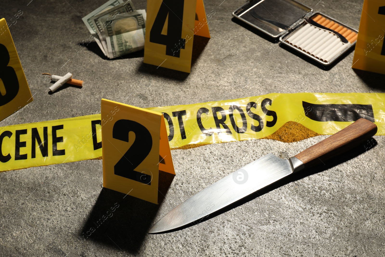 Forensic expertise. Crime scene with evidence, markers and police tape on grey background, closeup Photo of Forensic expertise. Crime scene with evidence, markers and police tape on grey background, closeup