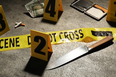Photo of Forensic expertise. Crime scene with evidence, markers and police tape on grey background, closeup