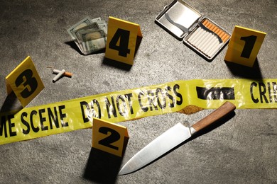 Photo of Forensic expertise. Crime scene with evidence, markers and police tape on grey background