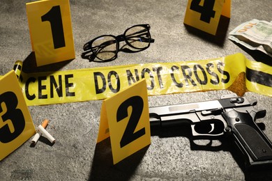 Photo of Forensic expertise. Crime scene with evidence, markers and police tape on grey background, closeup