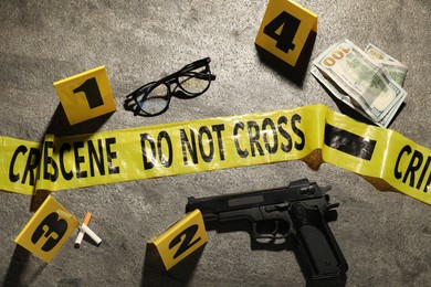 Photo of Forensic expertise. Crime scene with evidence, markers and police tape on grey background
