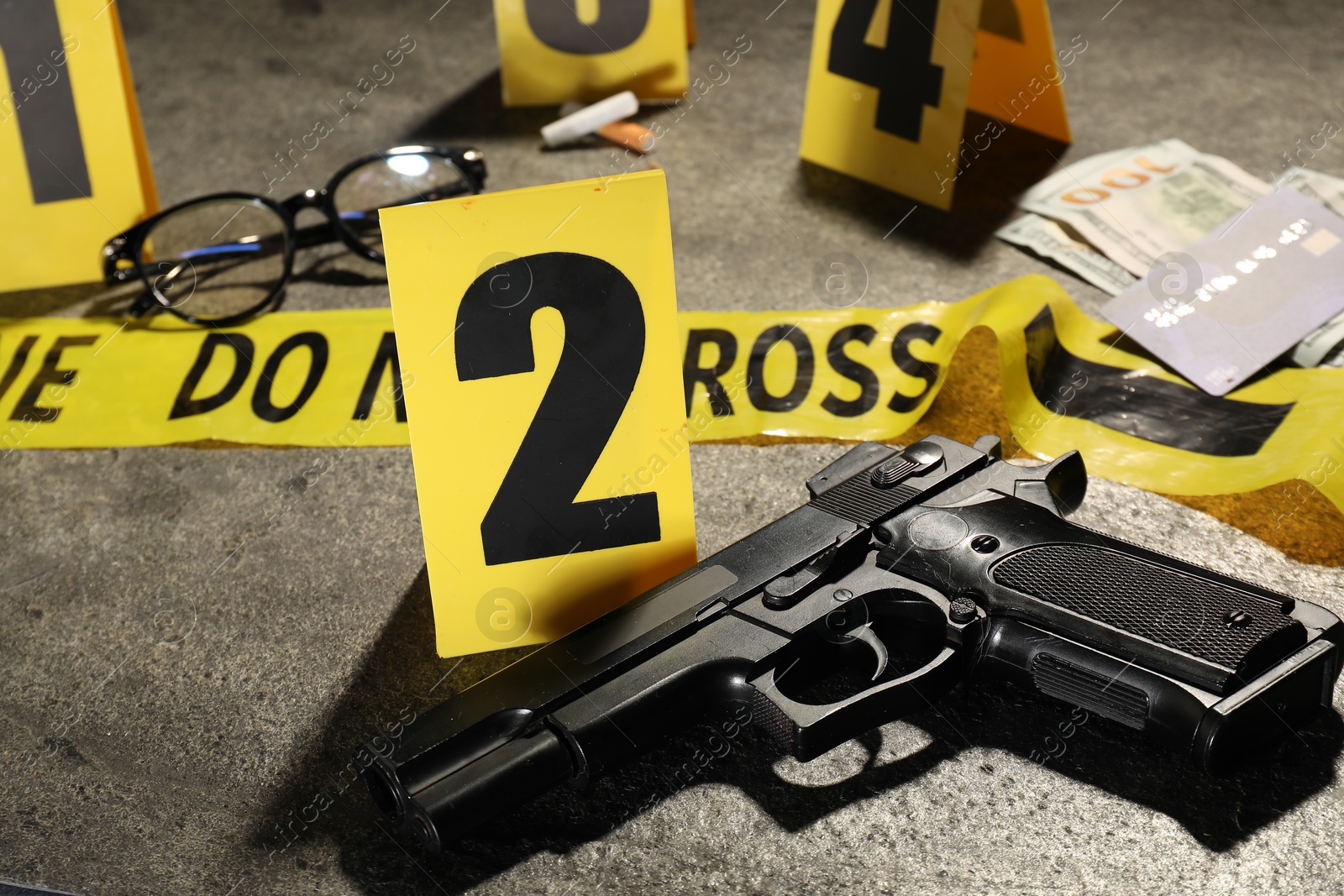 Forensic expertise. Crime scene with evidence, markers and police tape on grey background, closeup Photo of Forensic expertise. Crime scene with evidence, markers and police tape on grey background, closeup