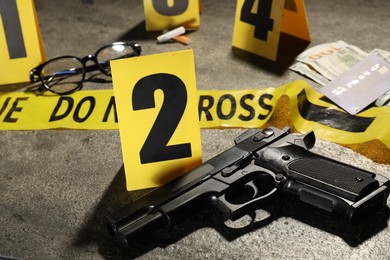 Photo of Forensic expertise. Crime scene with evidence, markers and police tape on grey background, closeup