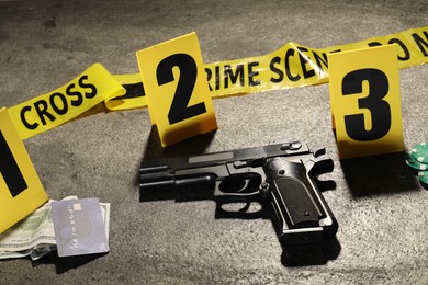 Photo of Forensic expertise. Crime scene with evidence, markers and police tape on grey background, closeup