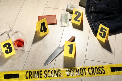 Photo of Forensic expertise. Crime scene with evidence, markers and police tape on floor
