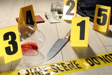 Photo of Forensic expertise. Crime scene with evidence, markers and police tape on floor, closeup