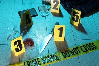 Photo of Forensic expertise. Crime scene with evidence, markers and police tape on floor. Color toned effect