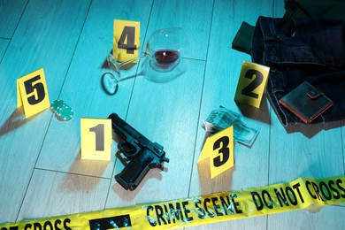 Photo of Forensic expertise. Crime scene with evidence, markers and police tape on floor. Color toned effect