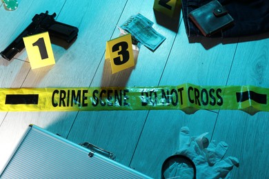 Photo of Forensic expertise. Crime scene with evidence, markers and police tape on floor. Color toned effect