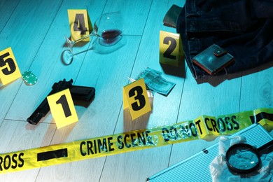 Photo of Forensic expertise. Crime scene with evidence, markers and police tape on floor. Color toned effect