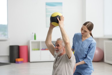 Photo of Doctor and patient exercising with medicine ball in clinic, space for text