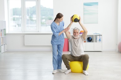 Photo of Doctor and patient exercising with medicine ball in clinic, space for text