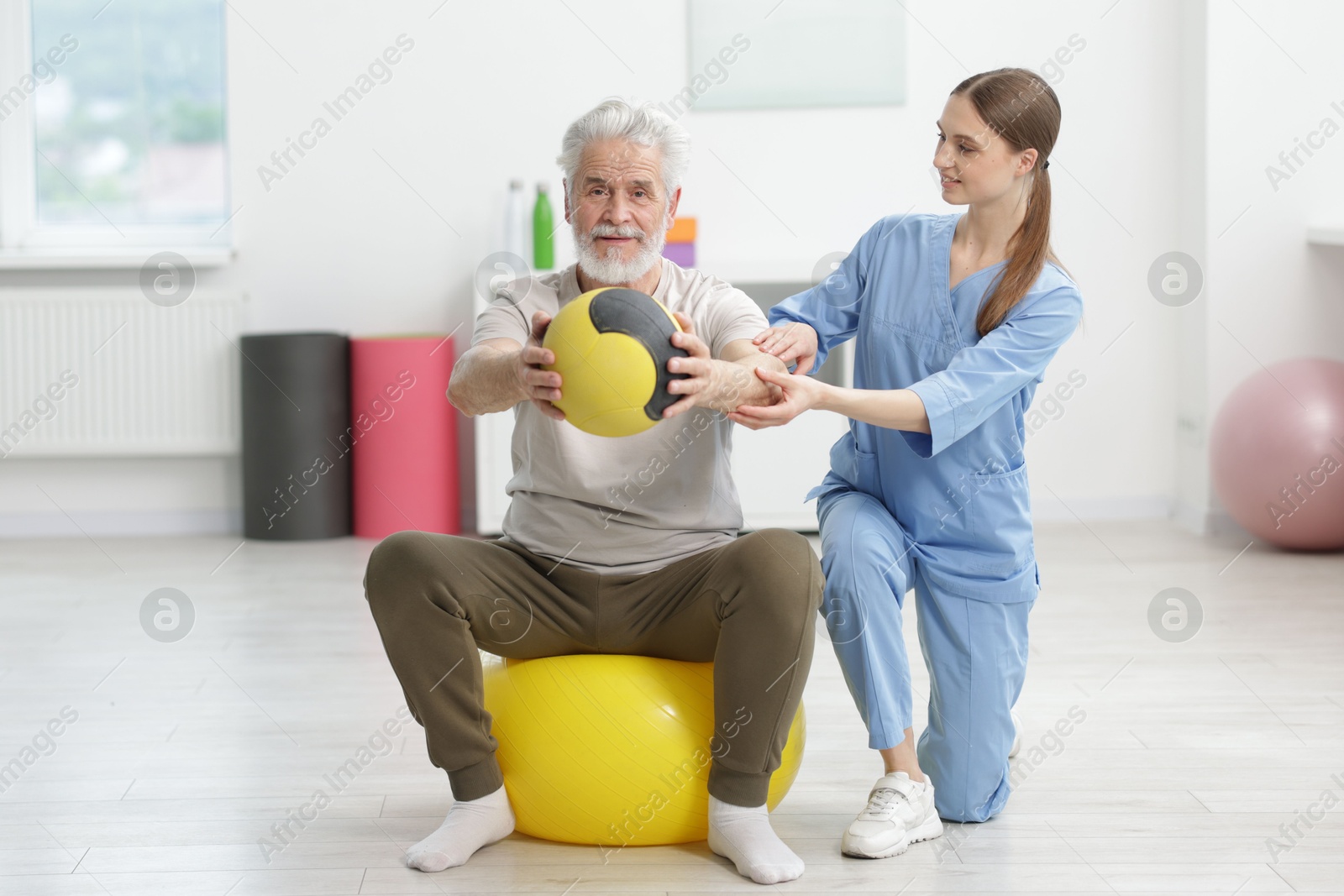 Doctor and patient exercising with medicine ball in clinic, space for text Photo of Doctor and patient exercising with medicine ball in clinic, space for text