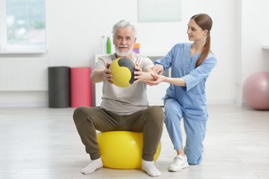 Photo of Doctor and patient exercising with medicine ball in clinic, space for text
