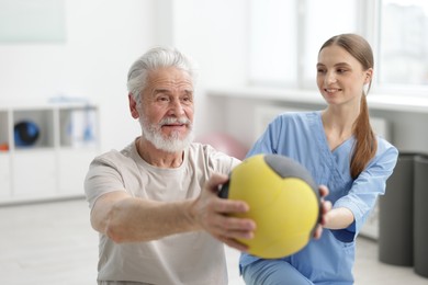 Photo of Doctor and patient exercising with medicine ball in clinic