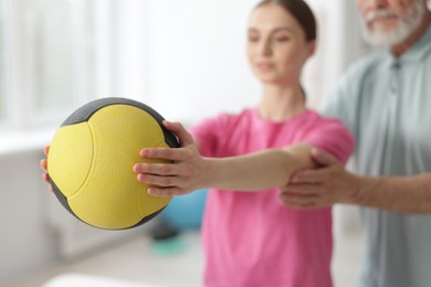 Photo of Doctor and patient exercising with medicine ball in clinic, selective focus
