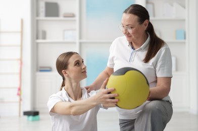 Photo of Doctor and patient exercising with medicine ball in clinic
