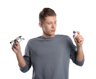 Photo of Man choosing between glasses and contact lenses on white background